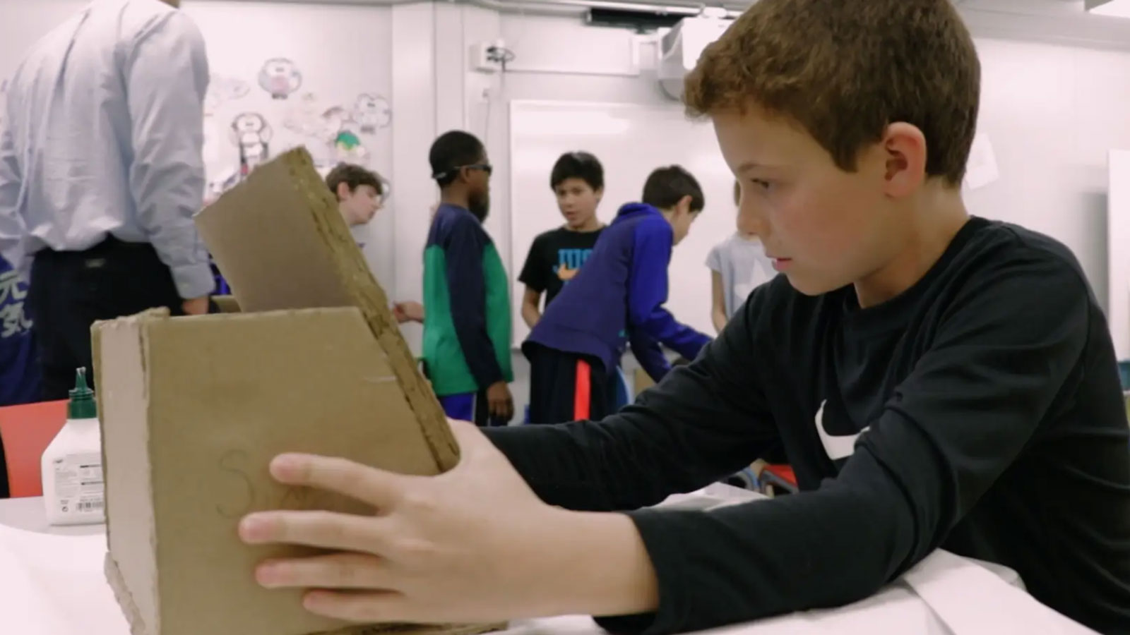A boy makes a reading easel out of cardboard.
