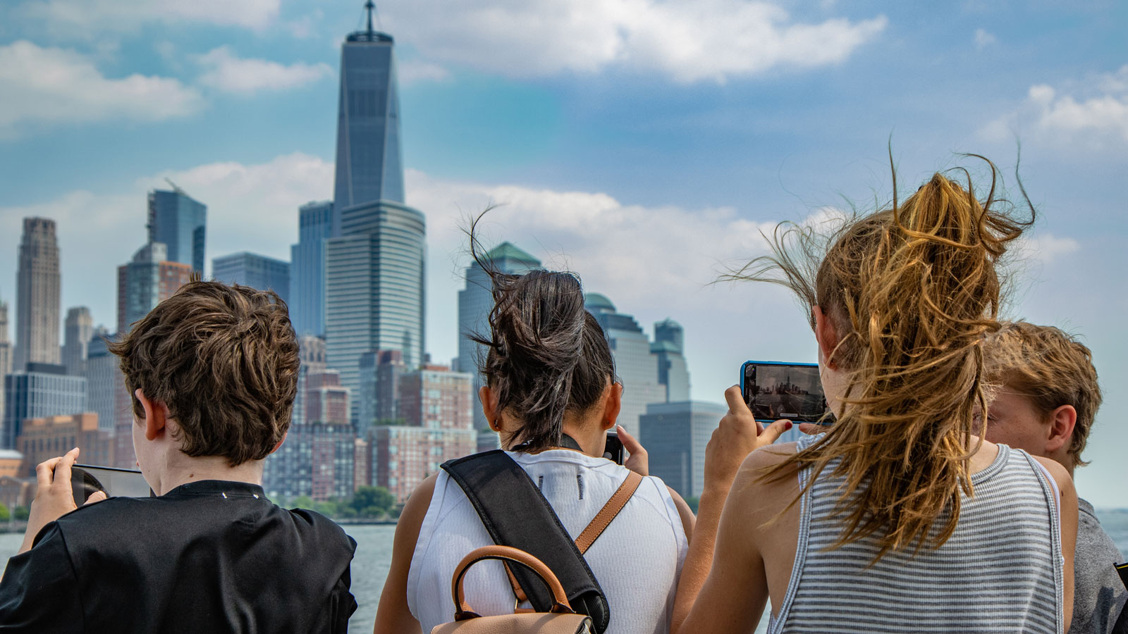 Students photograph the lower Manhattan skyline from a ferry in the Hudson River. 