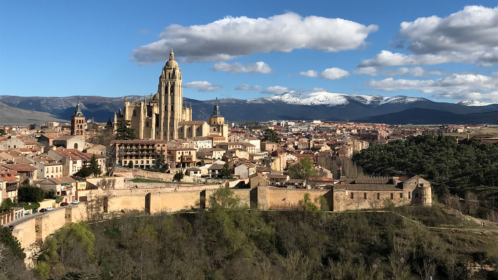 A historic walled city in Spain surrounded by mountains.