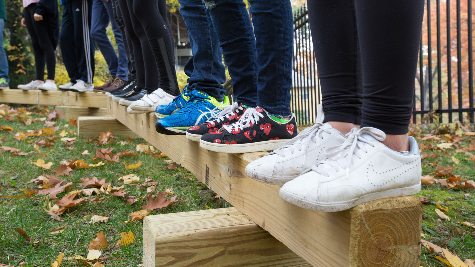 Middle Schoolers line up on a beam structure for an activity that involves balance and communication.