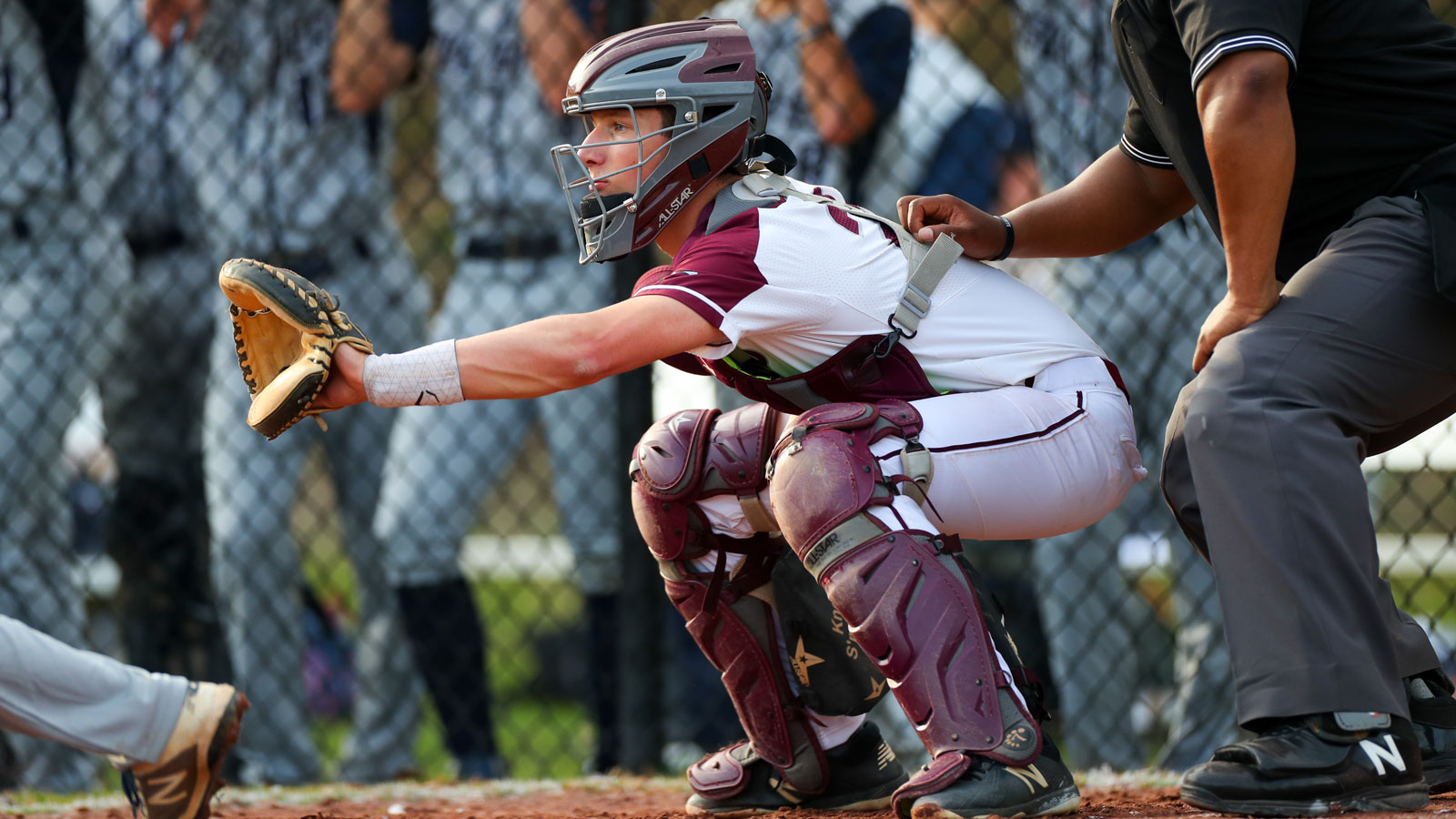 A catcher prepares for a pitch at the plate.