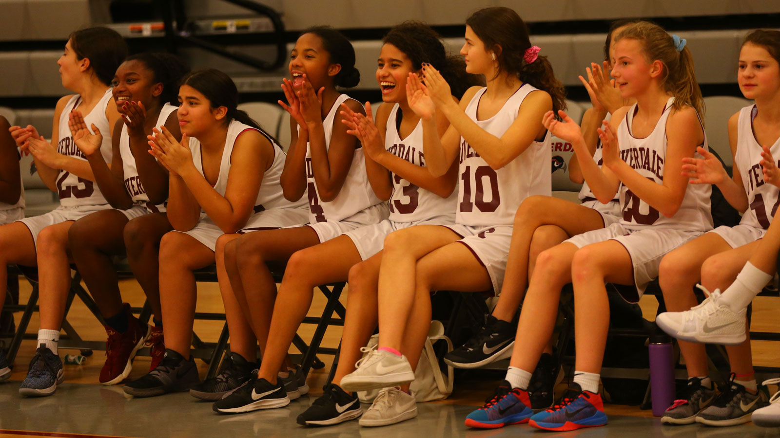 The Middle School girls basketball players applaud from the bench.