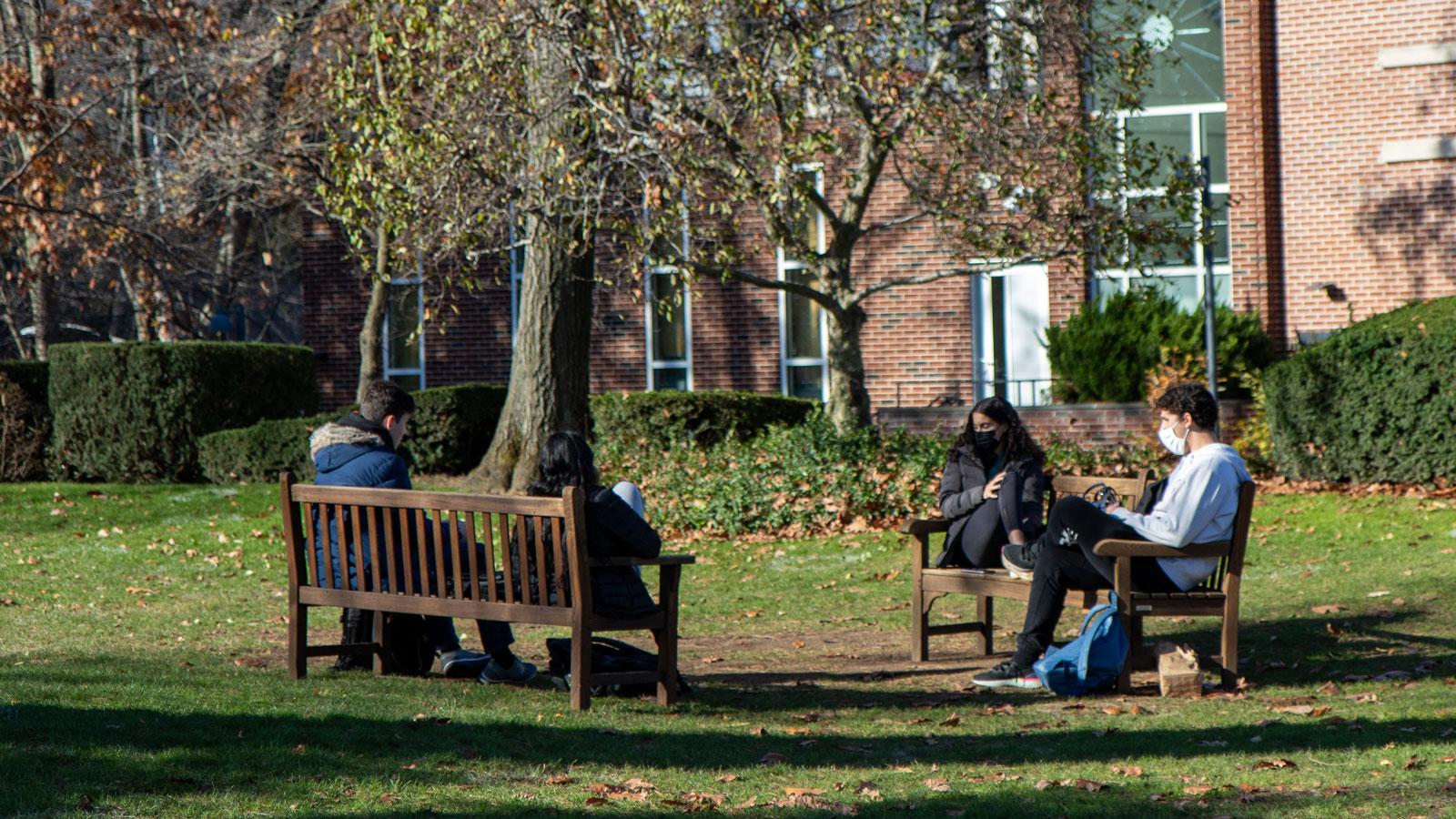 Students, sitting on benches, relax on Jones Lawn.