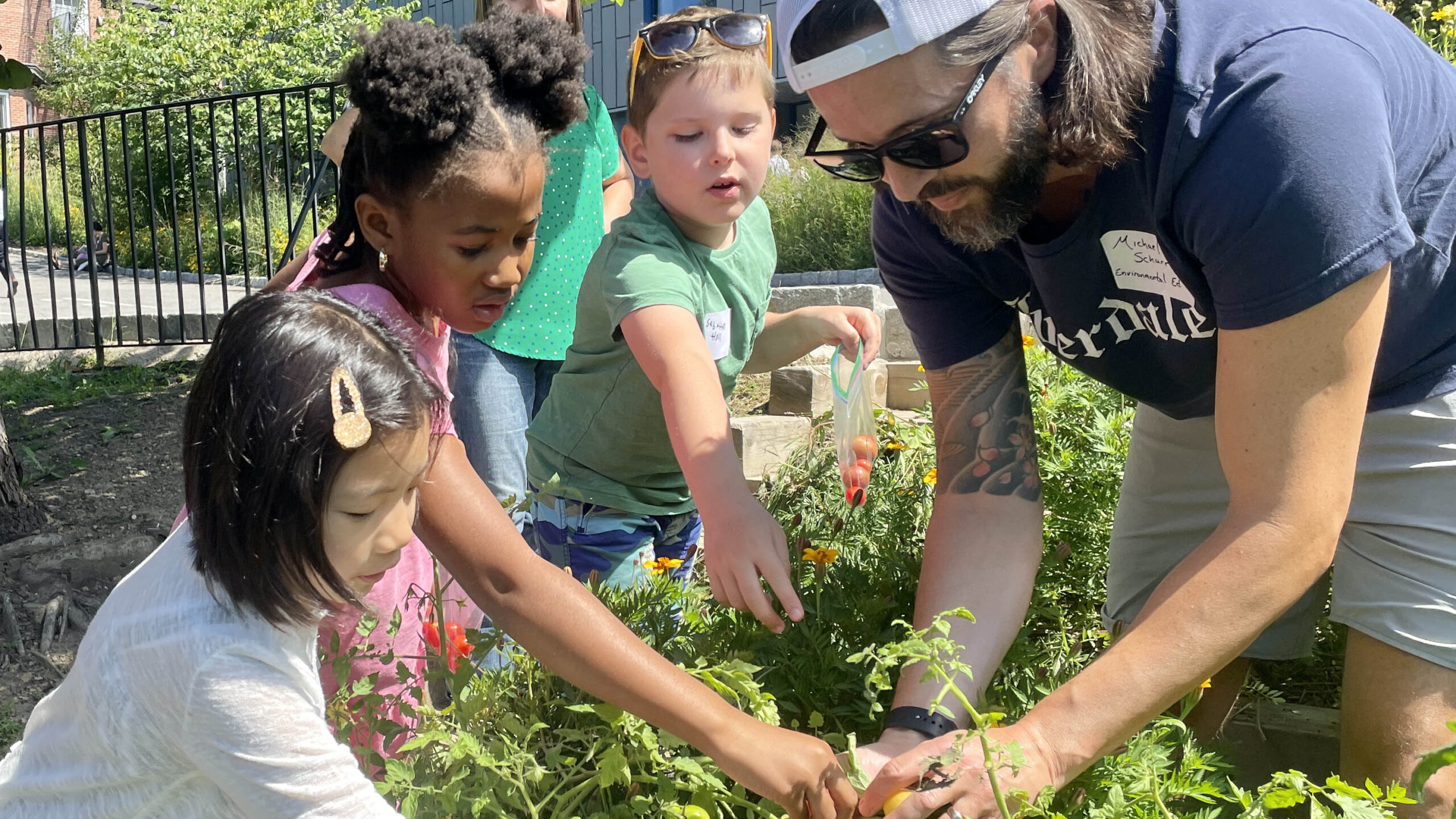 A teacher and students work in a garden