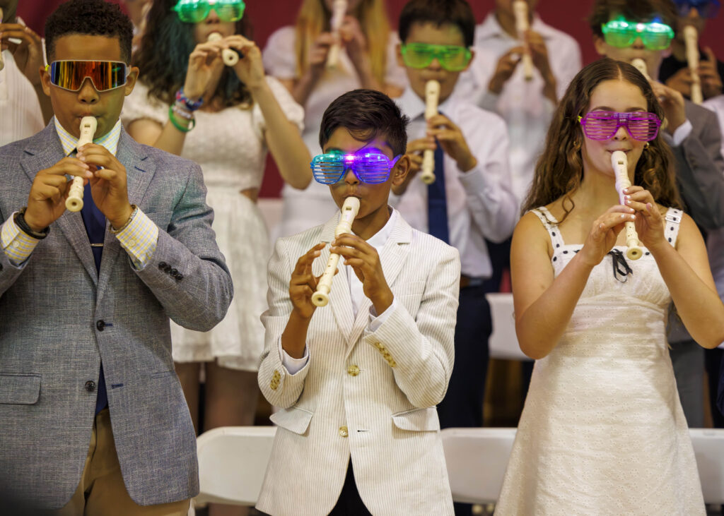 A group of students play recorders and wear sunglasses