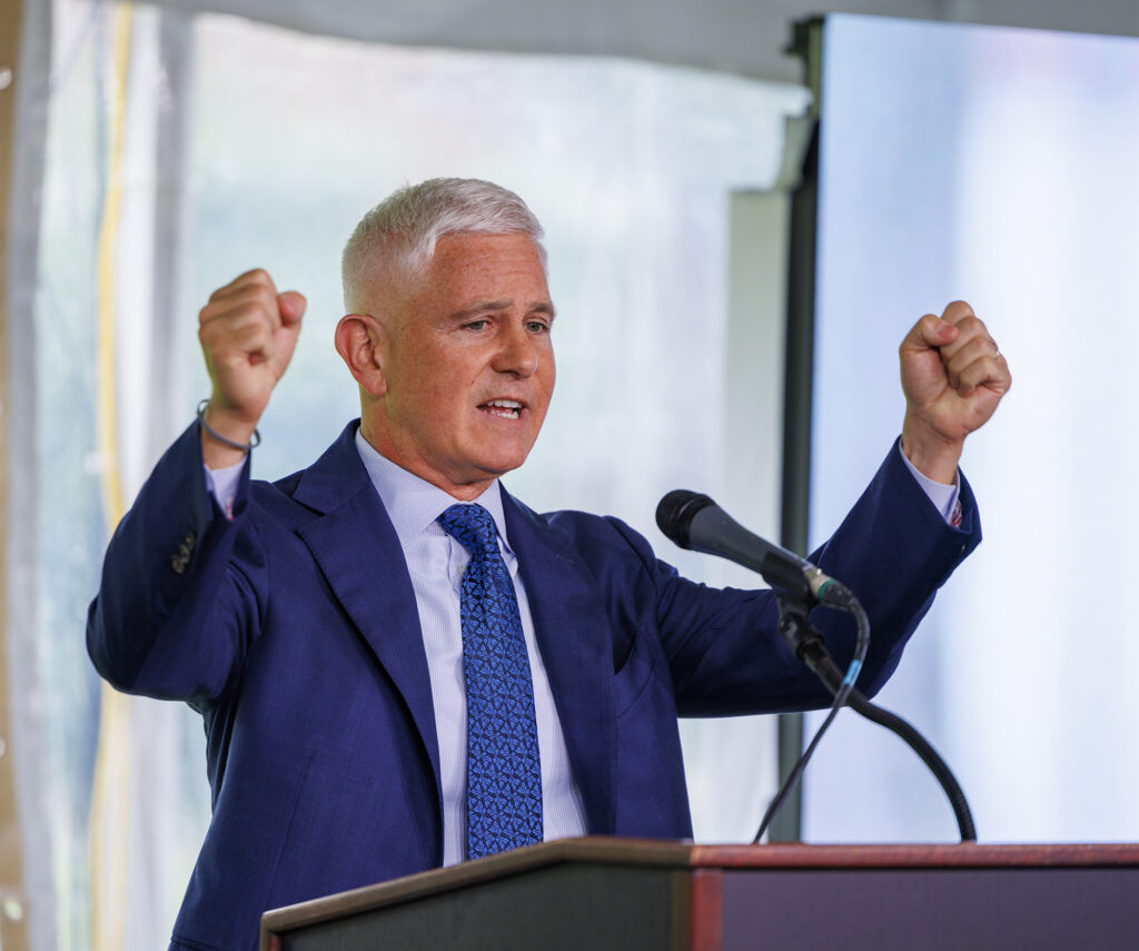 A man stands at a podium with his hands up in the air
