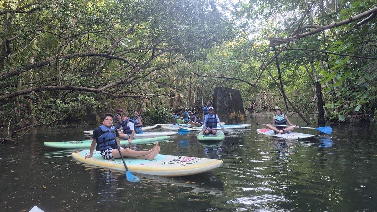 A group of students sit in canoes in water